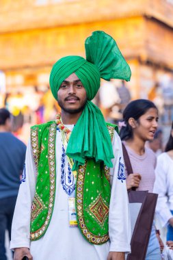 Faridabad, Haryana, India - February 17 2024: Portrait of a male sikh bhangra artist in traditional colorful dress and jewellery at surajkund crafts fair before they waiting for their performance.