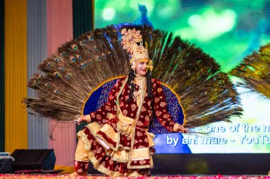 Ghaziabad, Uttar Pradesh, Hindistan - 17 Mart 2024: Renkli etnik giysiler içinde Holi Festivali sırasında tavus kuşu tüyleriyle phoolo ki holi 'yi oynayan genç erkek sanatçının portresi.