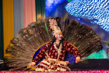 Ghaziabad, Uttar Pradesh, Hindistan - 17 Mart 2024: Renkli etnik giysiler içinde Holi Festivali sırasında tavus kuşu tüyleriyle phoolo ki holi 'yi oynayan genç erkek sanatçının portresi.