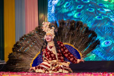 Ghaziabad, Uttar Pradesh, Hindistan - 17 Mart 2024: Renkli etnik giysiler içinde Holi Festivali sırasında tavus kuşu tüyleriyle phoolo ki holi 'yi oynayan genç erkek sanatçının portresi.