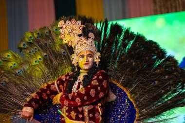 Ghaziabad, Uttar Pradesh, Hindistan - 17 Mart 2024: Renkli etnik giysiler içinde Holi Festivali sırasında tavus kuşu tüyleriyle phoolo ki holi 'yi oynayan genç erkek sanatçının portresi.