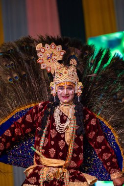 Ghaziabad, Uttar Pradesh, Hindistan - 17 Mart 2024: Renkli etnik giysiler içinde Holi Festivali sırasında tavus kuşu tüyleriyle phoolo ki holi 'yi oynayan genç erkek sanatçının portresi.