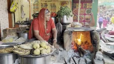 Puşkar, Rajasthan, Hindistan - 25 Kasım 2023: Hindistan 'da Hindistan' da yaşlı bir kadın çamur fırınında Hint yemeği hazırlıyor