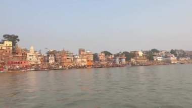 Varanasi, Uttar Pradesh, Hindistan - 21 Kasım 2022: Antik binaların ve Dashashwamedh ghat tapınaklarının mimari görüntüsü üzerine video Tahta bottan Ganj Nehri kıyısında. 