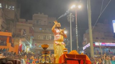 Varanasi, Uttar Pradesh, Hindistan - 21 Kasım 2022: Ganga aarti, Dashashwamedh ghat geleneksel elbise ve Hindu ayinleri ile kutsal nehir ganges akşam aarti performans genç rahip portresi.