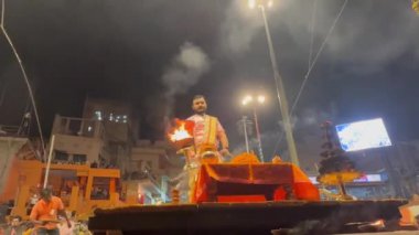 Varanasi, Uttar Pradesh, Hindistan - 21 Kasım 2022: Ganga aarti, Dashashwamedh ghat geleneksel elbise ve Hindu ayinleri ile kutsal nehir ganges akşam aarti performans genç rahip portresi.