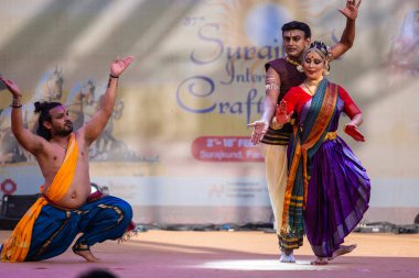 Faridabad, Haryana, Hindistan - 17 Şubat 2024: Etnik sanatlar fuarı sırasında erkek ve kadın Hintli sanatçılar sahnede klasik dans kuchipudi performansı sergiliyorlar. 