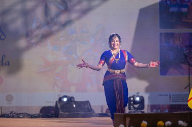 Faridabad, Haryana, Hindistan - 17 Şubat 2024: Güney Hintli kadın sanatçı geleneksel ipek sari ve mücevher fuarında klasik dans kuchipudi performansı sergiliyor. 