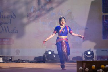 Faridabad, Haryana, Hindistan - 17 Şubat 2024: Güney Hintli kadın sanatçı geleneksel ipek sari ve mücevher fuarında klasik dans kuchipudi performansı sergiliyor. 