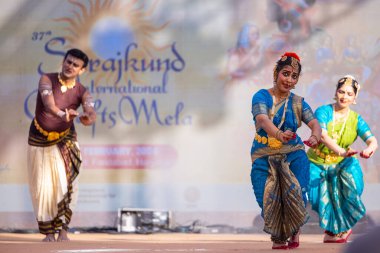 Faridabad, Haryana, India - February 17 2024: Group of male and female south indian artists performing classical dance kuchipudi on stage during surajkund crafts fair in ethnic costumes.  clipart