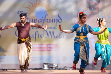 Faridabad, Haryana, Hindistan - 17 Şubat 2024: Etnik sanatlar fuarı sırasında erkek ve kadın Hintli sanatçılar sahnede klasik dans kuchipudi performansı sergiliyorlar. 
