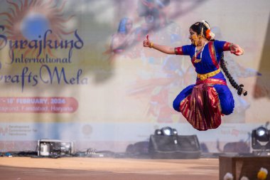 Faridabad, Haryana, Hindistan - 17 Şubat 2024: Güney Hintli kadın sanatçı geleneksel ipek sari ve mücevher fuarında klasik dans kuchipudi performansı sergiliyor. 