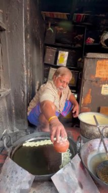 Varanasi, Uttar Pradesh, Hindistan - 21 Kasım 2022: Yaşlı bir aşçının Hint usulü tatlı Jalebi 'yi yaptığı video sabah kahvaltısı için Varanasi' deki şekerci dükkanında..