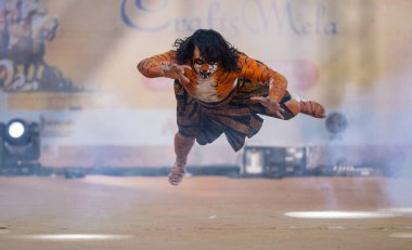 Faridabad, Haryana, India - February 17 2024: Portrait of an male artist performing classical dance kuchipudi as tiger to save himself from hunter on stage with tiger makeup on his face and body. clipart