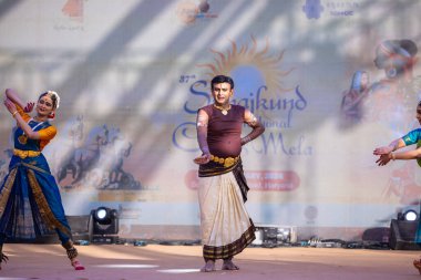 Faridabad, Haryana, India - February 17 2024: Group of male and female south indian artists performing classical dance kuchipudi on stage during surajkund crafts fair in ethnic costumes.  clipart