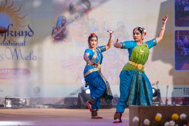 Faridabad, Haryana, India - February 17 2024: Female south indian artists performing classical dance kuchipudi at surajkund craft fair in traditional silk sarees and jewelry.  clipart