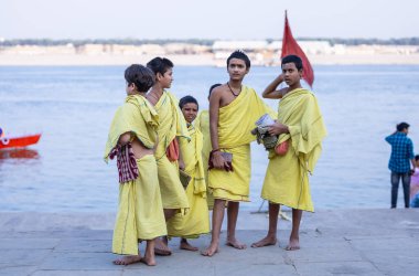 Varanasi, Uttar Pradesh, Hindistan - 05 Mart 2023: Ganj nehrinin kıyısında açık bir sınıfta çalışmak üzere duran gurukul 'un etnik sarı elbiseli genç erkek öğrencileri.