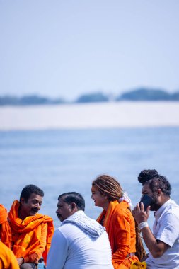 Varanasi, Uttar Pradesh, India - March 05th, 2023: Group of female sadhvi riding on wooden boat in holy river ganges during masan holi in varanasi clipart