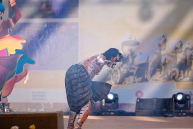 Faridabad, Haryana, Hindistan - 17 Şubat 2024: Yüzünde ve vücudunda kaplan makyajı ile sahnede kendini avcıdan kurtarmak için klasik dans Kuchipudi 'sini kaplan olarak sergileyen bir erkek sanatçının portresi.