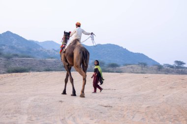 Puşkar, Rajasthan, Hindistan - 24 Kasım 2023: genç Hintli Rajasthani 'nin portresi. Annesi yakınlarda yerde yatıyor..