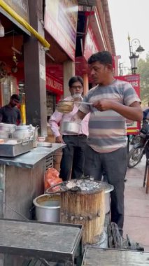 Varanasi, Uttar Pradesh, Hindistan - 24 Mart 2023: Sokak çayhanesi, Varanasi 'deki Dashashwamedh ghat' ta nehir çeteleri yakınında çay hazırlayan bir çay satıcısının portresi.