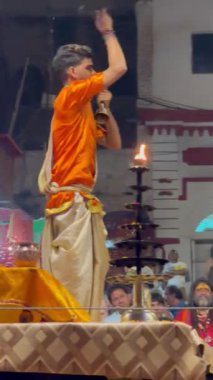 Varanasi, Uttar Pradesh, Hindistan - 21 Kasım 2022: Ganga aarti, Dashashwamedh ghat geleneksel elbise ve Hindu ayinleri ile kutsal nehir ganges akşam aarti performans genç rahip portresi.