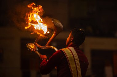 Varanasi, Uttar Pradesh, Hindistan - 18 Ocak 2024: Ganga aarti, Dashashwamedh Ghat geleneksel elbise ve Hindu ayinleri ile Ganj nehri akşam ayini yapan genç rahip portresi.