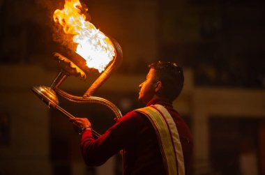 Varanasi, Uttar Pradesh, Hindistan - 18 Ocak 2024: Ganga aarti, Dashashwamedh Ghat geleneksel elbise ve Hindu ayinleri ile Ganj nehri akşam ayini yapan genç rahip portresi.