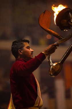 Varanasi, Uttar Pradesh, Hindistan - 18 Ocak 2024: Ganga aarti, Dashashwamedh Ghat geleneksel elbise ve Hindu ayinleri ile Ganj nehri akşam ayini yapan genç rahip portresi.