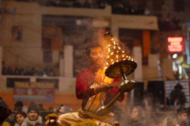 Varanasi, Uttar Pradesh, Hindistan - 18 Ocak 2024: Ganga aarti, Dashashwamedh Ghat geleneksel elbise ve Hindu ayinleri ile Ganj nehri akşam ayini yapan genç rahip portresi.