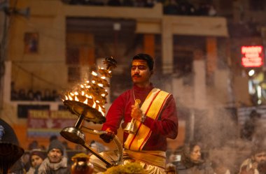 Varanasi, Uttar Pradesh, Hindistan - 18 Ocak 2024: Ganga aarti, Dashashwamedh Ghat geleneksel elbise ve Hindu ayinleri ile Ganj nehri akşam ayini yapan genç rahip portresi.