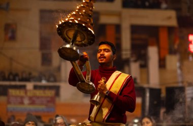 Varanasi, Uttar Pradesh, Hindistan - 18 Ocak 2024: Ganga aarti, Dashashwamedh Ghat geleneksel elbise ve Hindu ayinleri ile Ganj nehri akşam ayini yapan genç rahip portresi.