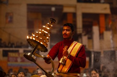 Varanasi, Uttar Pradesh, Hindistan - 18 Ocak 2024: Ganga aarti, Dashashwamedh Ghat geleneksel elbise ve Hindu ayinleri ile Ganj nehri akşam ayini yapan genç rahip portresi.