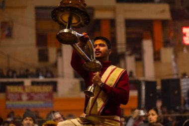 Varanasi, Uttar Pradesh, Hindistan - 18 Ocak 2024: Ganga aarti, Dashashwamedh Ghat geleneksel elbise ve Hindu ayinleri ile Ganj nehri akşam ayini yapan genç rahip portresi.
