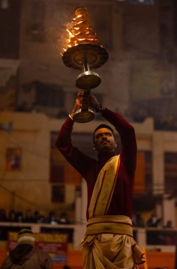 Varanasi, Uttar Pradesh, Hindistan - 18 Ocak 2024: Ganga aarti, Dashashwamedh Ghat geleneksel elbise ve Hindu ayinleri ile Ganj nehri akşam ayini yapan genç rahip portresi.