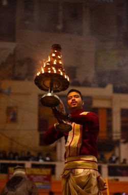 Varanasi, Uttar Pradesh, Hindistan - 18 Ocak 2024: Ganga aarti, Dashashwamedh Ghat geleneksel elbise ve Hindu ayinleri ile Ganj nehri akşam ayini yapan genç rahip portresi.