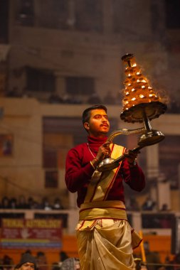 Varanasi, Uttar Pradesh, Hindistan - 18 Ocak 2024: Ganga aarti, Dashashwamedh Ghat geleneksel elbise ve Hindu ayinleri ile Ganj nehri akşam ayini yapan genç rahip portresi.