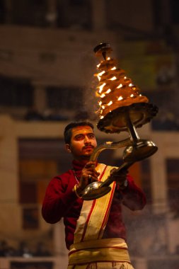 Varanasi, Uttar Pradesh, Hindistan - 18 Ocak 2024: Ganga aarti, Dashashwamedh Ghat geleneksel elbise ve Hindu ayinleri ile Ganj nehri akşam ayini yapan genç rahip portresi.