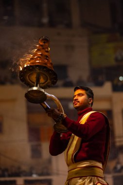 Varanasi, Uttar Pradesh, Hindistan - 18 Ocak 2024: Ganga aarti, Dashashwamedh Ghat geleneksel elbise ve Hindu ayinleri ile Ganj nehri akşam ayini yapan genç rahip portresi.