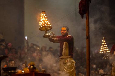 Varanasi, Uttar Pradesh, Hindistan - 18 Ocak 2024: Ganga aarti, Dashashwamedh Ghat geleneksel elbise ve Hindu ayinleri ile Ganj nehri akşam ayini yapan genç rahip portresi.