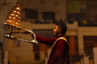 Varanasi, Uttar Pradesh, Hindistan - 18 Ocak 2024: Ganga aarti, Dashashwamedh Ghat geleneksel elbise ve Hindu ayinleri ile Ganj nehri akşam ayini yapan genç rahip portresi.