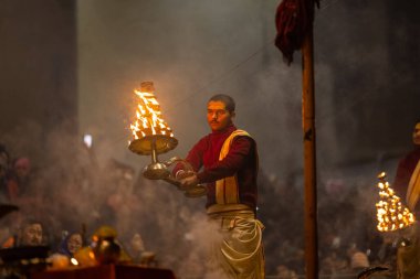 Varanasi, Uttar Pradesh, Hindistan - 18 Ocak 2024: Ganga aarti, Dashashwamedh Ghat geleneksel elbise ve Hindu ayinleri ile Ganj nehri akşam ayini yapan genç rahip portresi.