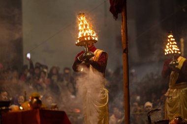 Varanasi, Uttar Pradesh, Hindistan - 18 Ocak 2024: Ganga aarti, Dashashwamedh Ghat geleneksel elbise ve Hindu ayinleri ile Ganj nehri akşam ayini yapan genç rahip portresi.