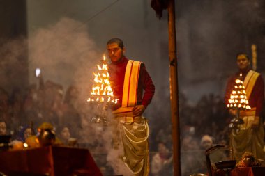 Varanasi, Uttar Pradesh, Hindistan - 18 Ocak 2024: Ganga aarti, Dashashwamedh Ghat geleneksel elbise ve Hindu ayinleri ile Ganj nehri akşam ayini yapan genç rahip portresi.