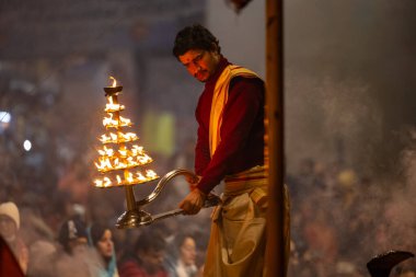 Varanasi, Uttar Pradesh, Hindistan - 18 Ocak 2024: Ganga aarti, Dashashwamedh Ghat geleneksel elbise ve Hindu ayinleri ile Ganj nehri akşam ayini yapan genç rahip portresi.