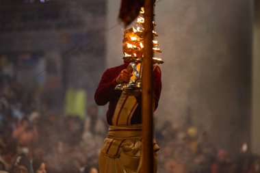 Varanasi, Uttar Pradesh, Hindistan - 18 Ocak 2024: Ganga aarti, Dashashwamedh Ghat geleneksel elbise ve Hindu ayinleri ile Ganj nehri akşam ayini yapan genç rahip portresi.