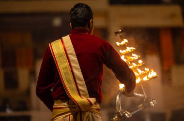 Varanasi, Uttar Pradesh, Hindistan - 18 Ocak 2024: Ganga aarti, Dashashwamedh Ghat geleneksel elbise ve Hindu ayinleri ile Ganj nehri akşam ayini yapan genç rahip portresi.