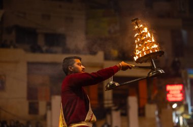 Varanasi, Uttar Pradesh, Hindistan - 18 Ocak 2024: Ganga aarti, Dashashwamedh Ghat geleneksel elbise ve Hindu ayinleri ile Ganj nehri akşam ayini yapan genç rahip portresi.
