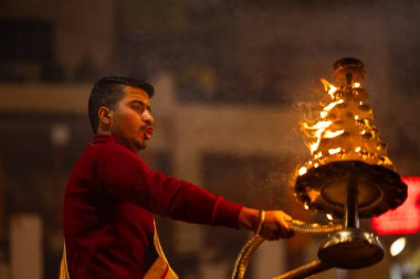 Varanasi, Uttar Pradesh, Hindistan - 18 Ocak 2024: Ganga aarti, Dashashwamedh Ghat geleneksel elbise ve Hindu ayinleri ile Ganj nehri akşam ayini yapan genç rahip portresi.