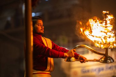 Varanasi, Uttar Pradesh, Hindistan - 18 Ocak 2024: Ganga aarti, Dashashwamedh Ghat geleneksel elbise ve Hindu ayinleri ile Ganj nehri akşam ayini yapan genç rahip portresi.